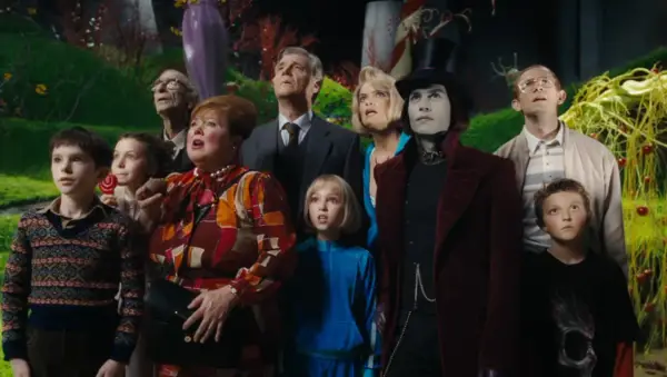 A group of children and adults, including Willy Wonka, look up in awe in a fantastical candy landscape.