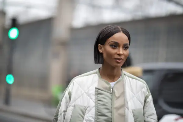 Une femme au regard intense arbore une coupe carré long impeccable, vêtue d'une veste matelassée tendance.