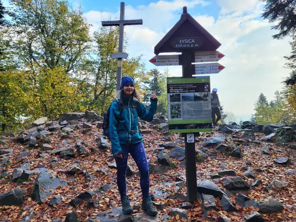 Uśmiechnięta turystka na szczycie Łysicy, 614 m n.p.m. Jesienne liście i kamienie wokół.