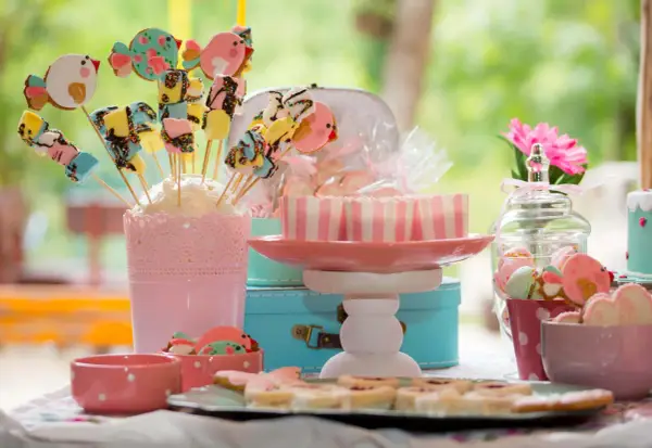 Una encantadora mesa de chuches casera con galletas de pájaros, malvaviscos y dulces en tonos pastel.