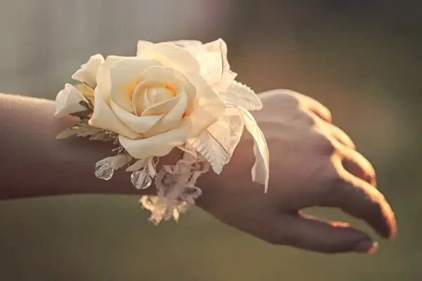 Delikatny corsage po polsku z kremową różą, koronką i kryształkami na nadgarstku.