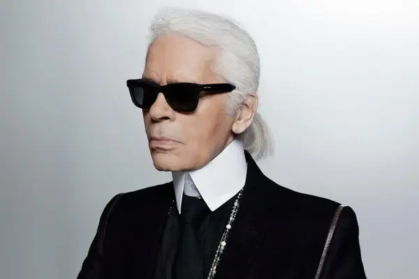 Ikona stylu, Karl Lagerfeld, w czarnym garniturze i okularach. Kto to? Ikona mody.