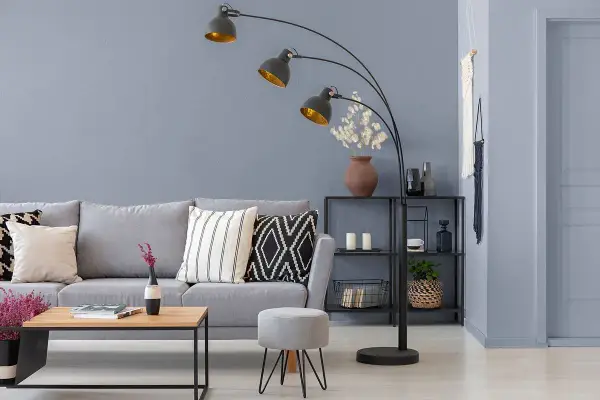Nowoczesny salon z szarymi ścianami, wygodną sofą i designerską lampą łukową.