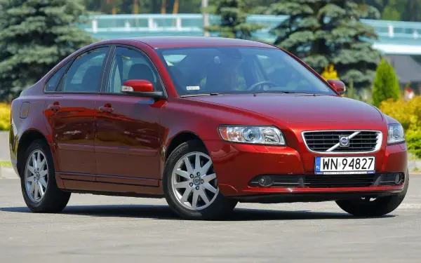 Czerwone Volvo S40 II z polskimi tablicami rejestracyjnymi WN 94827 zaparkowane na zewnątrz.