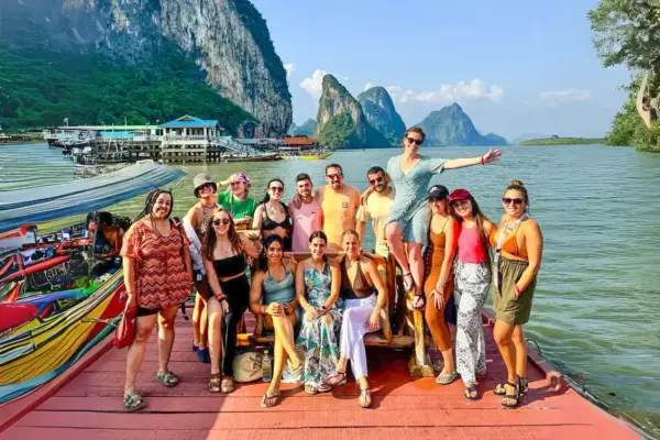 Grupo de amigos disfrutando en un barco en Tailandia, con islas kársticas al fondo. ¡Parece la mejor época para viajar a Tailandia!
