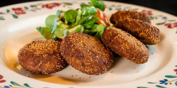Crocchette dorate e croccanti, un classico su cosa mangiare in Lombardia, servite con un'insalatina fresca.