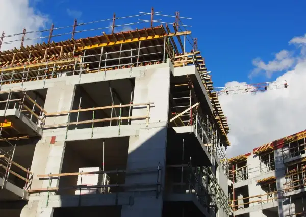 Rohbau eines Mehrfamilienhauses im Rahmen der Entwicklung von urbane gebiete. Gerüste und Betonstrukturen unter blauem Himmel.