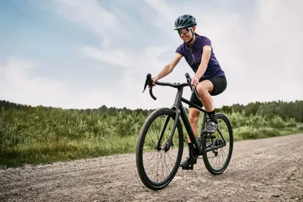 Kobieta na rowerze pokonuje szutrową drogę, wybierając trasę gravel czy cross.