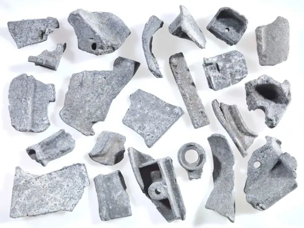 Kawałki metalu, gotowe do recyklingu metalu. Różnorodne kształty i rozmiary, niektóre z otworami, świadczą o ich przemysłowym pochodzeniu.