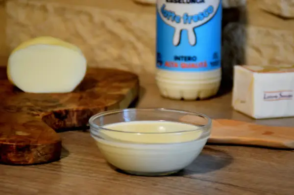 Una ciotola di cremosa fonduta di scamorza affumicata, con latte fresco e burro, pronta per essere gustata.