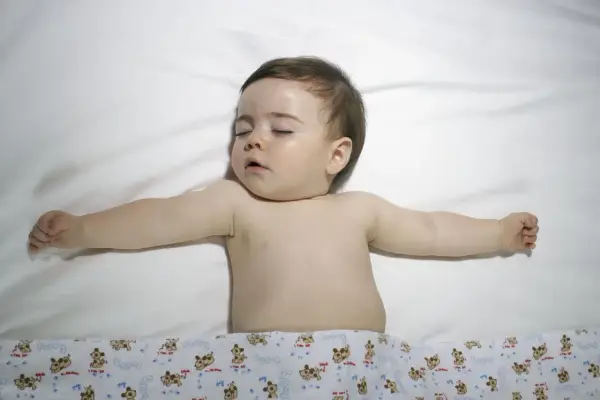 Śpiące dziecko z rozłożonymi rączkami. Choć obrazek nie sugeruje zespołu Turnera, warto pamiętać o jego istnieniu.