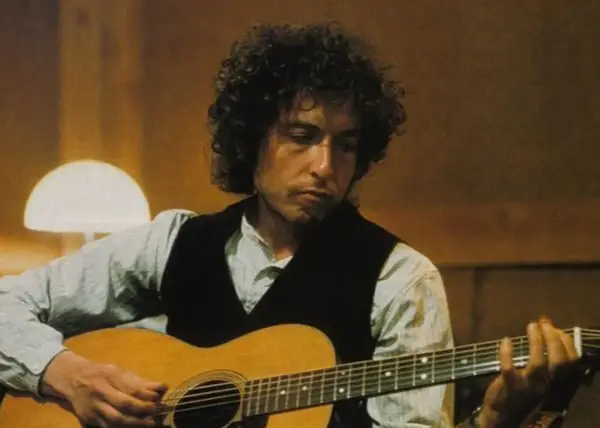 Bob Dylan gra na gitarze, tworząc swoje legendarne utwory.