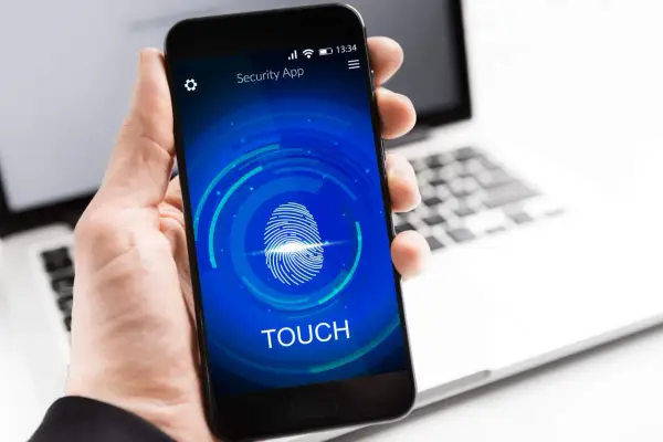 Dłoń trzyma smartfon z ekranem blokady "Security App" i ikoną odcisku palca. Proces autoryzacji jest w toku.