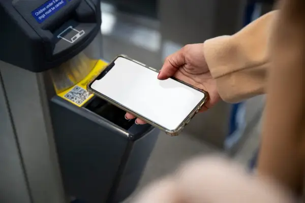 Dłoń zbliża smartfon do czytnika biletów. Szybkie płatności przez Euronet, bez prowizji PKO.