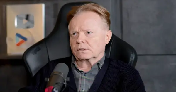 Michał Bajor siedzi w fotelu, przed mikrofonem, z nagrodą YouTube w tle.