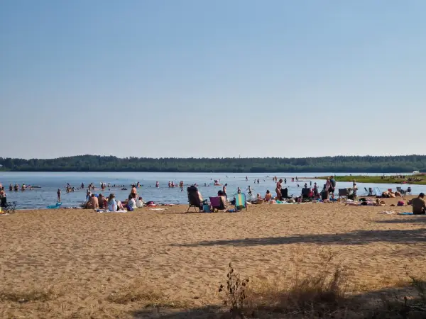 Folk njuter av solen och badar vid en strand, en perfekt plats för camping i Luleå.