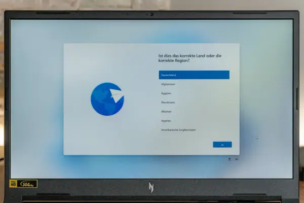 Ein Laptop zeigt die Windows 11 Einrichtung mit der Länderauswahl. Hier kann man Windows 11 ohne Microsoft Konto einrichten, indem man Deutschland wählt.