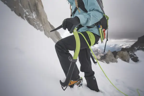 Alpinista używa czekana do wspinaczki po ośnieżonym zboczu. To narzędzie, co to jest czekan, pomaga w utrzymaniu równowagi i pokonywaniu trudnego terenu.