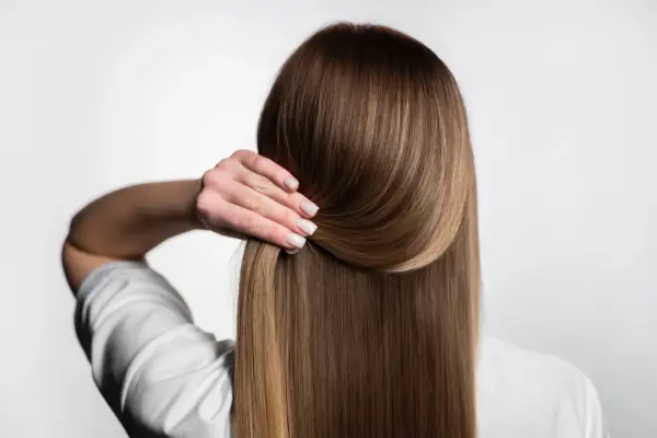 Capelli lisci e setosi, senza crespo, grazie a una routine efficace. La mano accarezza la chioma lucente.