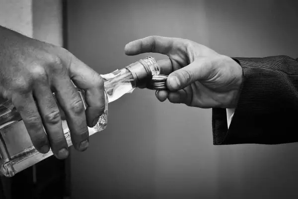 Dwie dłonie, jedna trzyma butelkę, druga odbiera klucz. To symbol tego, co powoduje alkohol: utratę kontroli i kluczy do własnego życia.