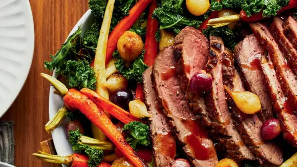 Tranches de magret de canard juteux, accompagnées de carottes rôties, d'oignons grelots et de chou frisé. Un plat savoureux et coloré.