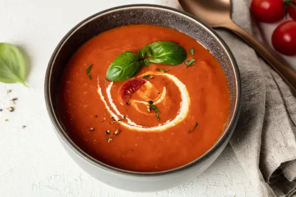 Eine cremige, vegane Tomatensuppe mit Basilikum und einem Klecks Sahne. Perfekt für kalte Tage.