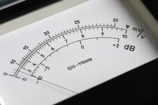 Wskaźnik miernika pokazuje poziom dźwięku w decybelach (dB). Skala obejmuje wartości od -10 do 30 dB, z dodatkowymi oznaczeniami mV/V.
