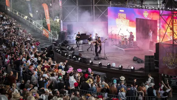 Na scenie podczas Piknik Country Mrągowo gra zespół, a publiczność w kapeluszach bawi się w rytm muzyki.