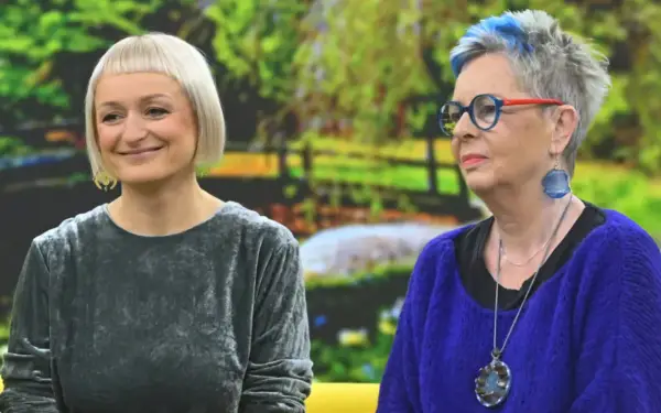 Dwie kobiety, jedna z krótkimi blond włosami, druga z siwymi z niebieskimi pasemkami, rozmawiają. Może facet 30 lat bez dziewczyny szuka rady u przyjaciółki?