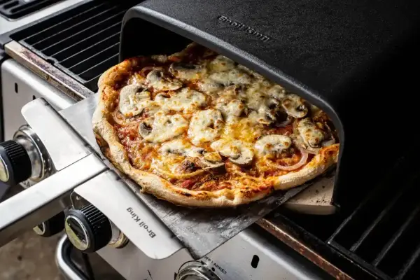 Pyszna pizza z pieczarkami i serem, właśnie wyjęta z pieca grillowego. Idealna do dzielenia się z przyjaciółmi, bo ile piec pizze, tyle radości!
