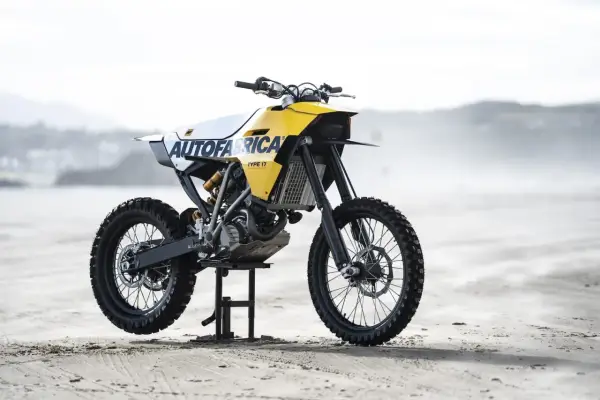 Żółto-biały motocykl customowy Autofabrica Type 17, bazujący na BMW G450X, stoi na plaży.