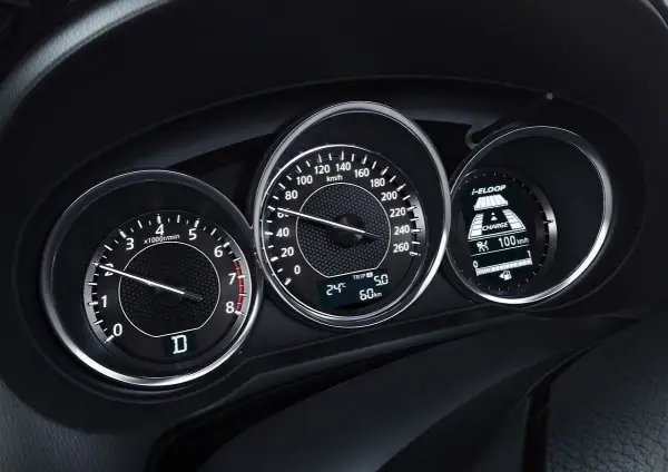 Deska rozdzielcza z obrotomierzem, prędkościomierzem i wyświetlaczem i-ELOOP. Widać falujące obroty silnika i prędkość 100 km/h.