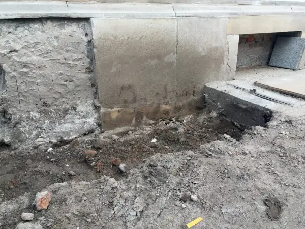 Prace przy podbijaniu fundamentów. Widoczny wykop i fragmenty muru.
