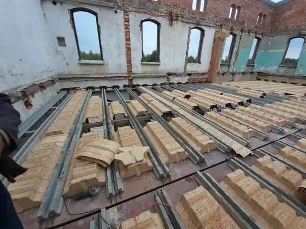 Rozpoczęła się wymiana stropu w starym domu. Metalowe belki i prefabrykowane elementy stropowe czekają na montaż.