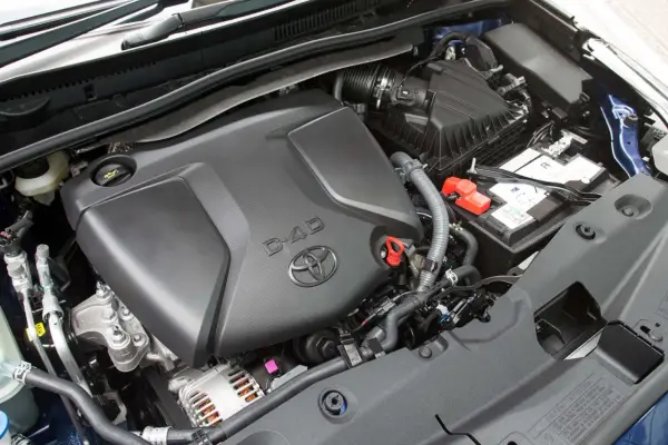 Silnik D-4D w Toyota Avensis T27. Widoczny jest czarny plastikowy dekiel silnika z logo Toyoty i napisem D-4D, akumulator oraz elementy układu dolotowego.