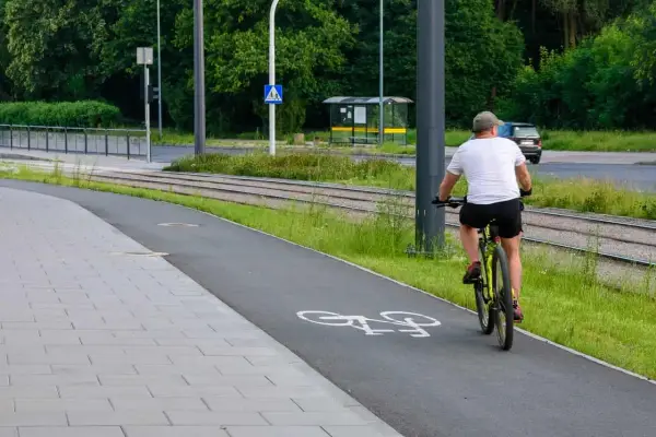 Mężczyzna na rowerze na ścieżce, obok torów tramwajowych. Uważaj, bo mandat za prowadzenie roweru pod wpływem alkoholu jest wysoki.