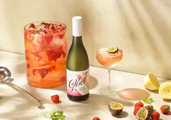 En stor bålskål fylld med jordgubbar och is, en flaska vitt vin och en cocktail med passionsfrukt. Perfekt för en somrig drink med vitt vin.