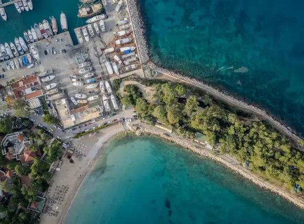 Widok z lotu ptaka na port i plażę w Kemerze, Turcja. Widać liczne jachty, łodzie, budynki i zielone tereny. To idealne miejsce na odkrywanie atrakcji Kemer.
