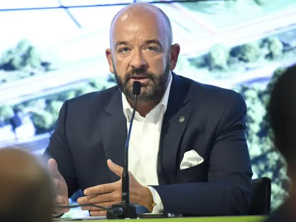 Jacek Sutryk z partnerem podczas konferencji prasowej. Mężczyzna w garniturze przemawia do mikrofonu.