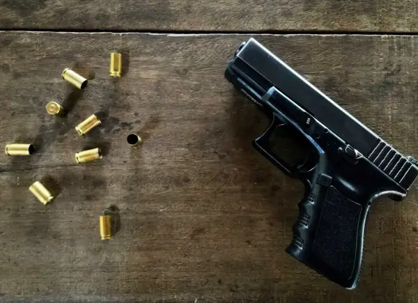 Czarny pistolet i łuski na drewnianym stole. Jaka broń na pozwolenie kolekcjonerskie?