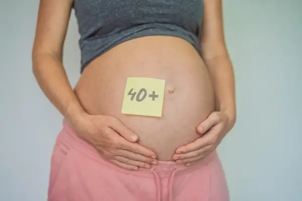 Brzuch kobiety w ciąży z karteczką "40+". To dowód, że ciąża po 40. jest możliwa i piękna.