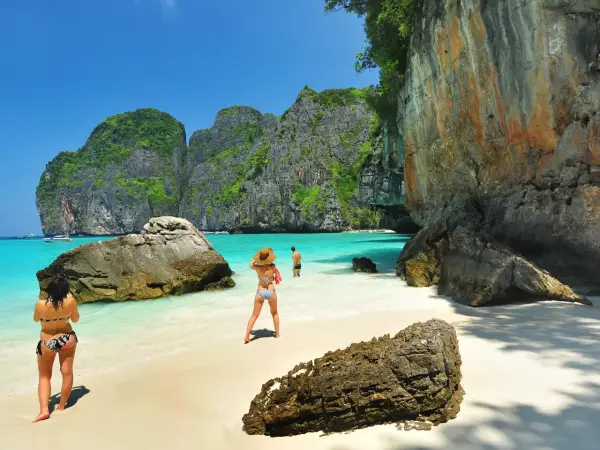Två personer njuter av det turkosa vattnet och de dramatiska klipporna vid Maya Bay, Thailand.