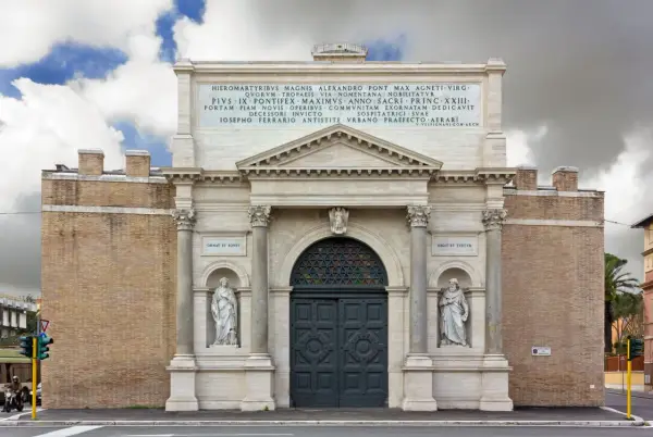 La Porta Pia, con le sue statue e iscrizioni, si erge maestosa sotto un cielo nuvoloso.