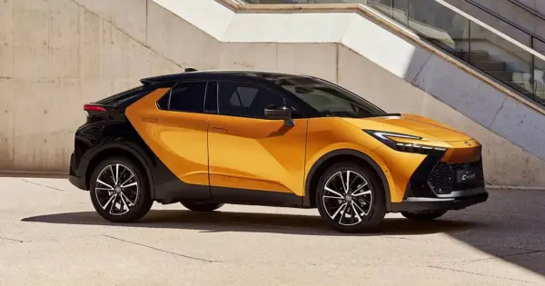 Nowy Toyota C-HR GR w kolorze pomarańczowo-czarnym, z dynamiczną linią nadwozia, zaparkowany przy betonowej ścianie.