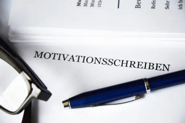 Okulary i długopis leżą obok dokumentu z napisem "MOTIVATIONSSCHREIBEN".