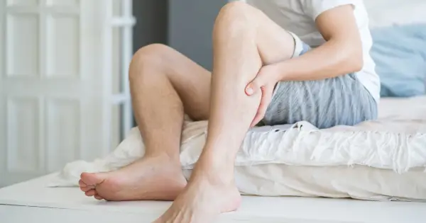 Mężczyzna trzyma się za łydkę, odczuwając ból. Może to być jeden z objawów miażdżycy, który wpływa także na psychikę.