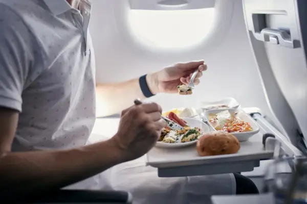 Pasażer je posiłek na pokładzie samolotu. Zastanawiasz się, czy można przewozić jedzenie w bagażu rejestrowanym Ryanair?