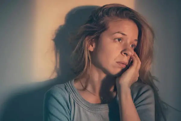 Une femme songeuse, le regard perdu, se demande : "suis je sous l'emprise d'un manipulateur test ?" Son visage exprime le doute et l'inquiétude.