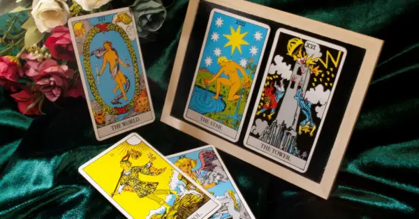 Karty tarota: Świat, Gwiazda, Wieża i inne z małych arkanów na aksamitnym tle.