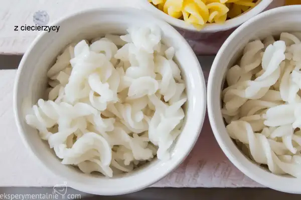 Biały makaron bez glutenu z ciecierzycy w miseczkach, obok żółtego makaronu.